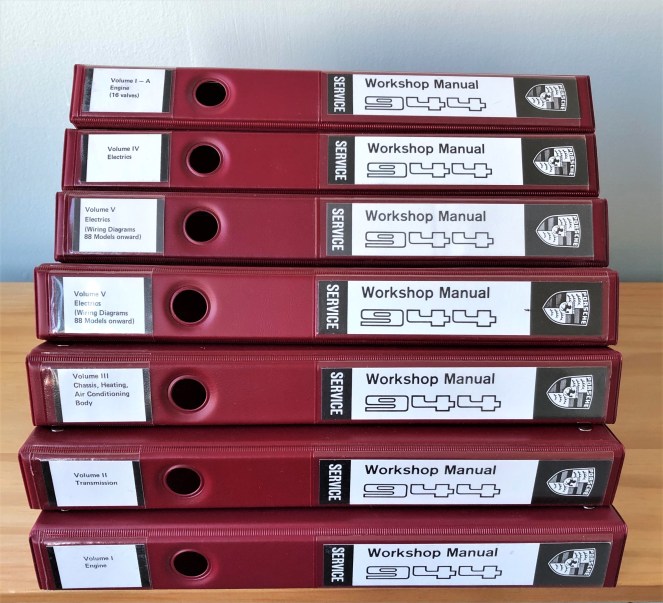 stack of 7 maroon binders labeled Porsche 944