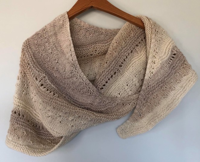 cream and mocha colored shawl draped on wooden hanger