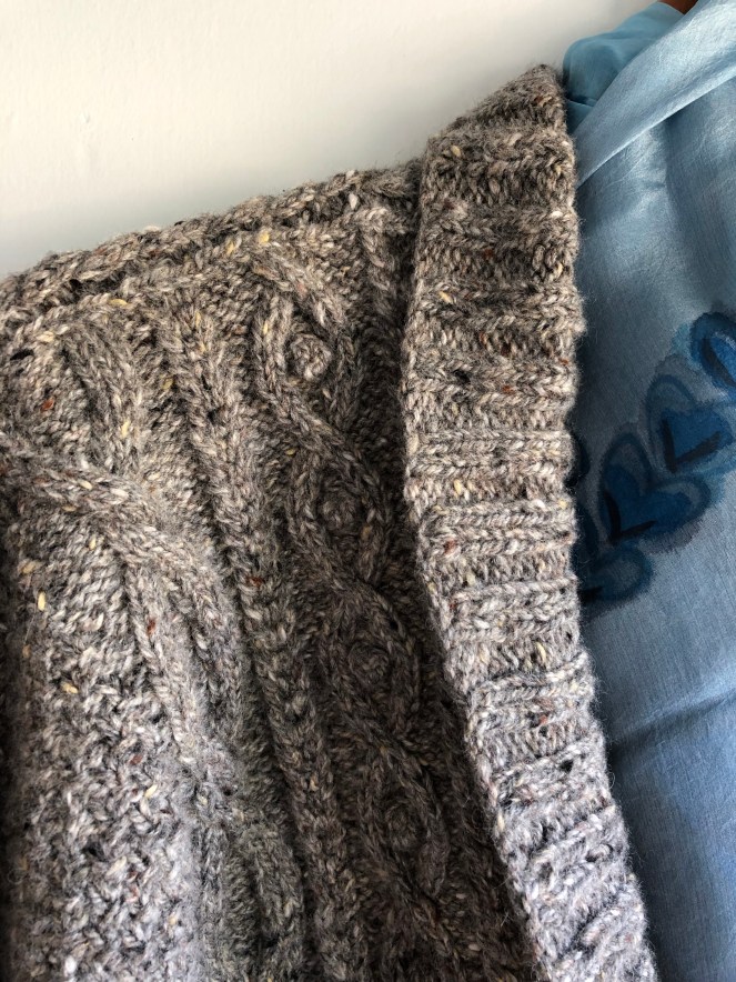 shoulder of gray knit sweater with cables and bobbles