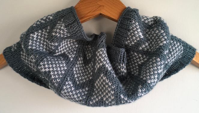 green and white knit cowl on wooden hanger