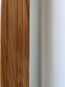 bare wood trim piece against pale green wall
