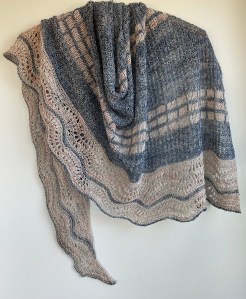 handknit blue shawl with contracting cream colored bands and lace edge