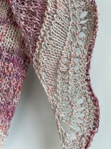 close up of hand knit pick shawl with contracting cream colored bands and lace edge