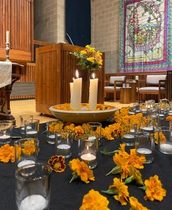 marigold blossoms scattered among white votive lights on a black table cloth