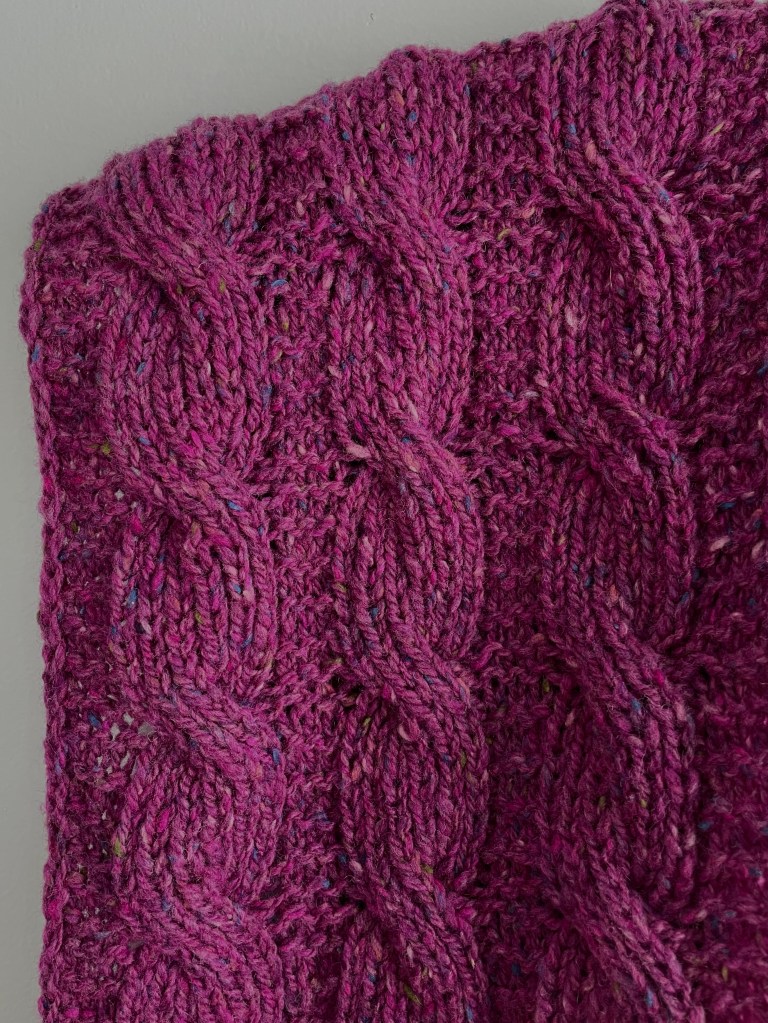 hand knit cable scarf in magenta tweed yarn with close up of twisted cables