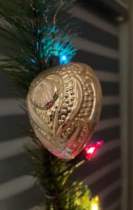 heart shaped antique glass Christmas ornament on tree with three lights (blue, red and yellow)
