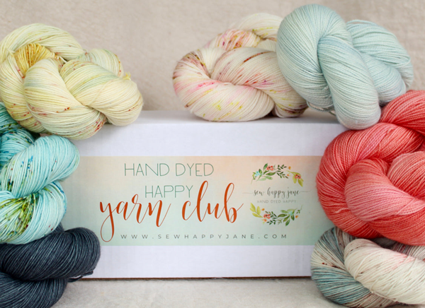 white mailing box surrounded by skeins of different colored yarn