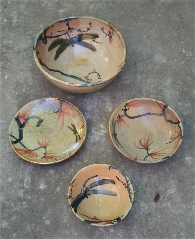four multicolored pottery bowls with dragonfly motifs on a gray background