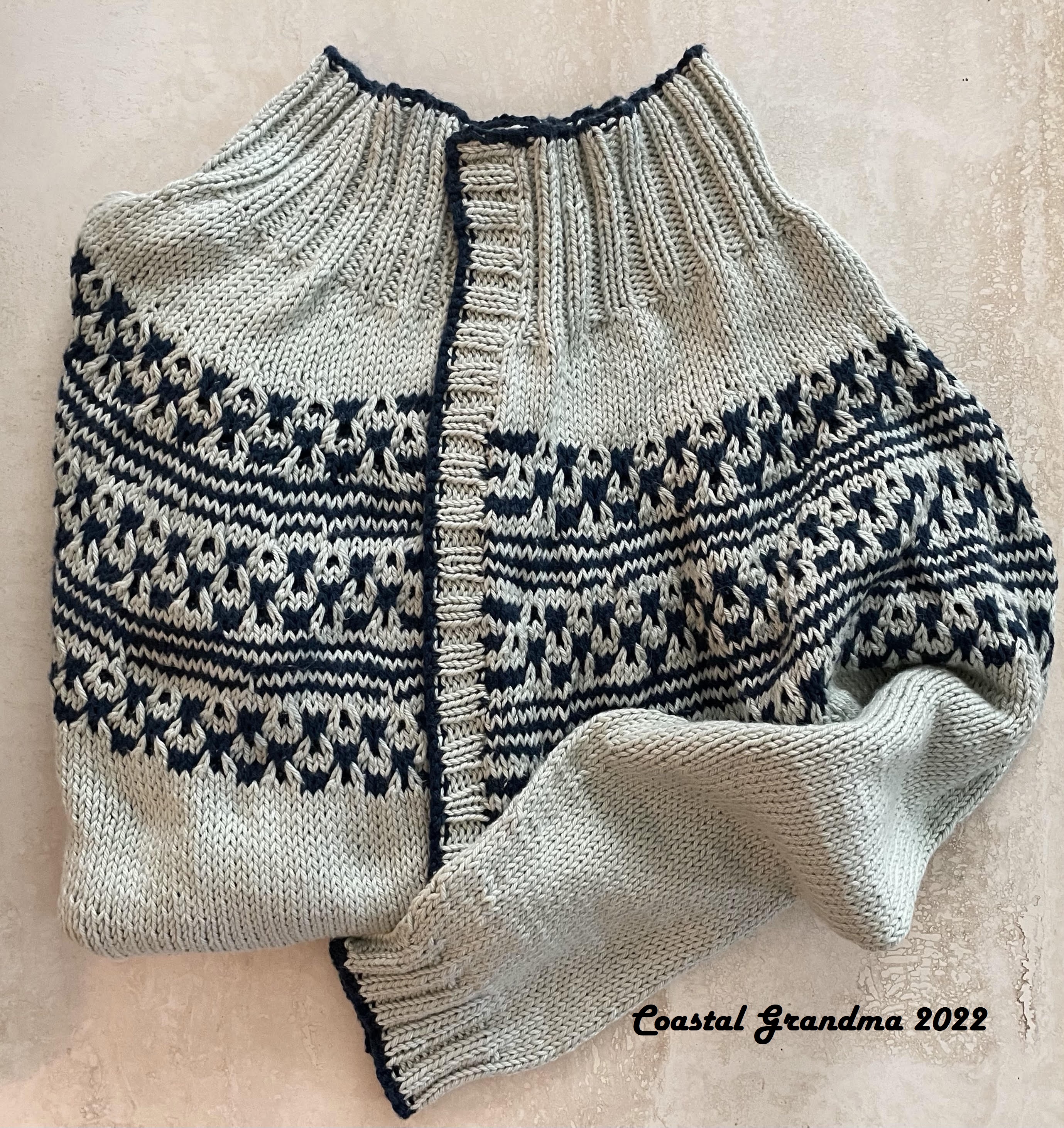 folded light green sweater with navy blue accents on yoke and note that reads Coastal Grandma 2022