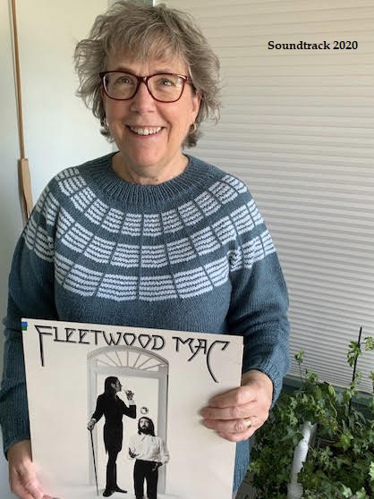 modeling handknit teal sweater with white accents and holding a Fleetwood Mac album cover