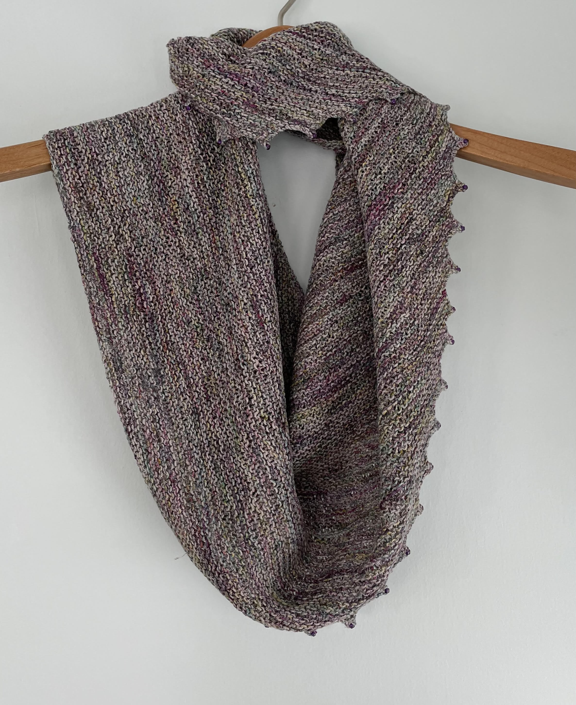 varigated lavender handknit scarf on a wooden hanger