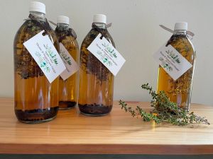 four vinegar bottles on wooden table with a sprig of thyme