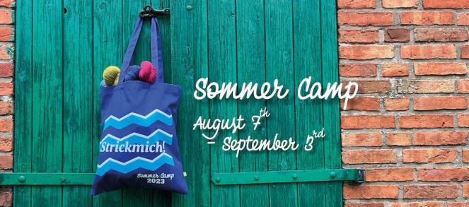 blue bag with yarn hanging on a green door with the German words strickmich sommer camp