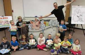Author Derek Anderson and a group of children each holding a copy of his book, 10 Pigs
