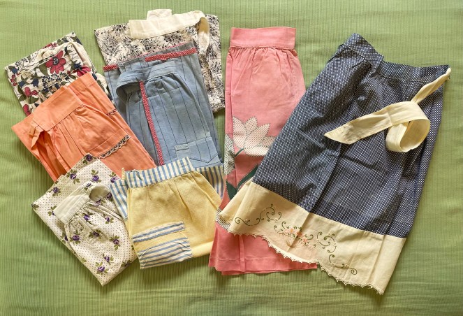 8 aprons laid out on a green background