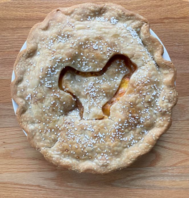 peach pie with decorative sugar and chicken cookie cutter outline on top crust