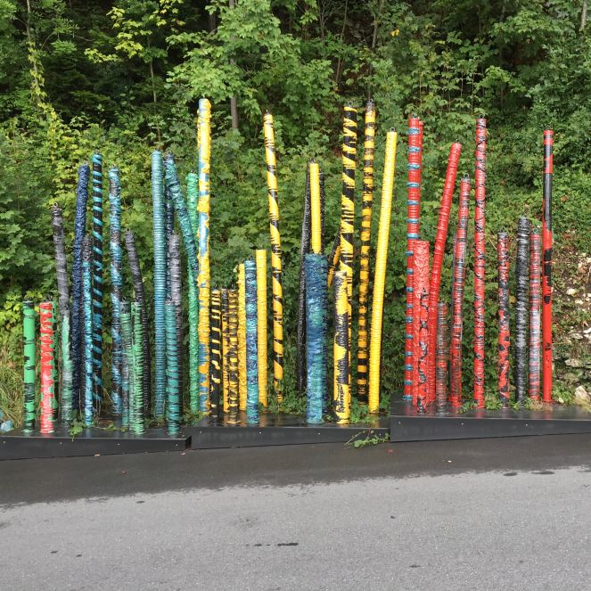 artistic colorful posts set against a forest background with tarmac road in foreground