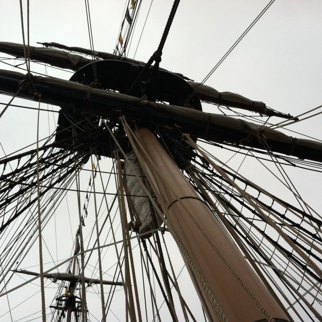looking skyward up a main mast into the rigging of a tall ship