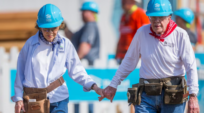 Jimmy and Rosalyn Carter holding hands and dressed in work clothes, tools and hard hats