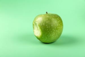 lime green background and Granny Smith apple with one bite taken