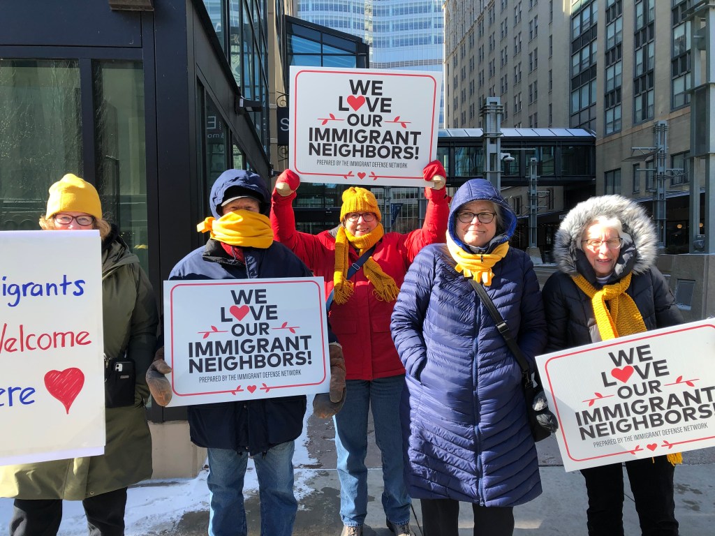 five peopl holding protest signs and wearing bright gold scarves