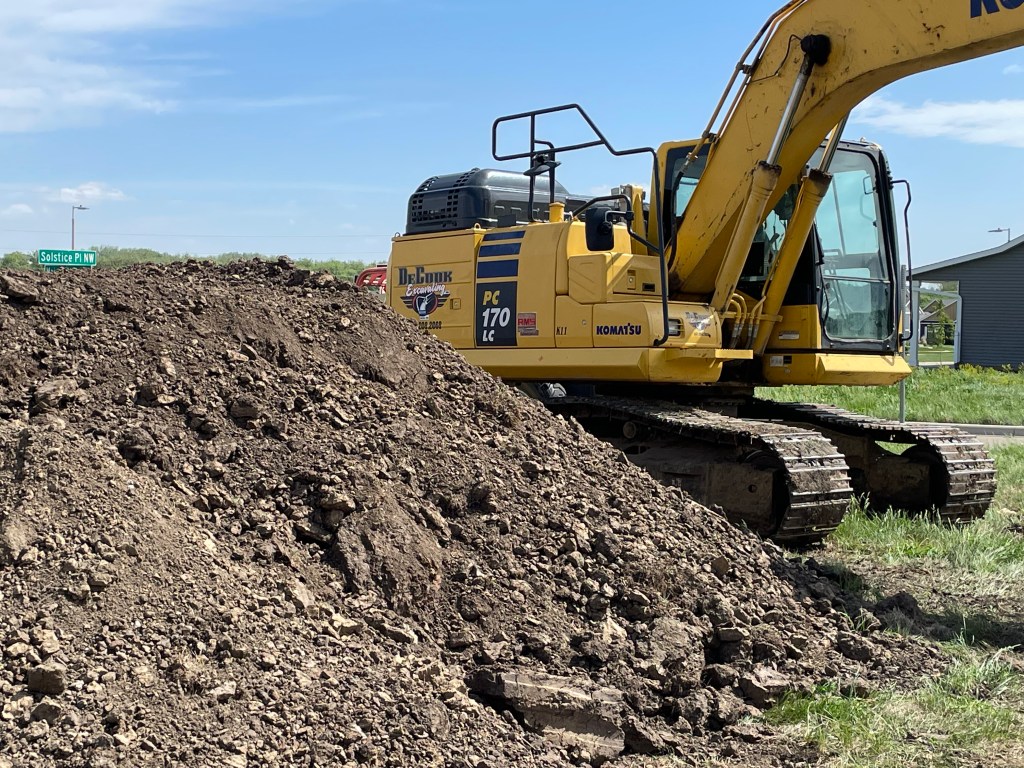 large dirt pile and yellow earth moving equipment