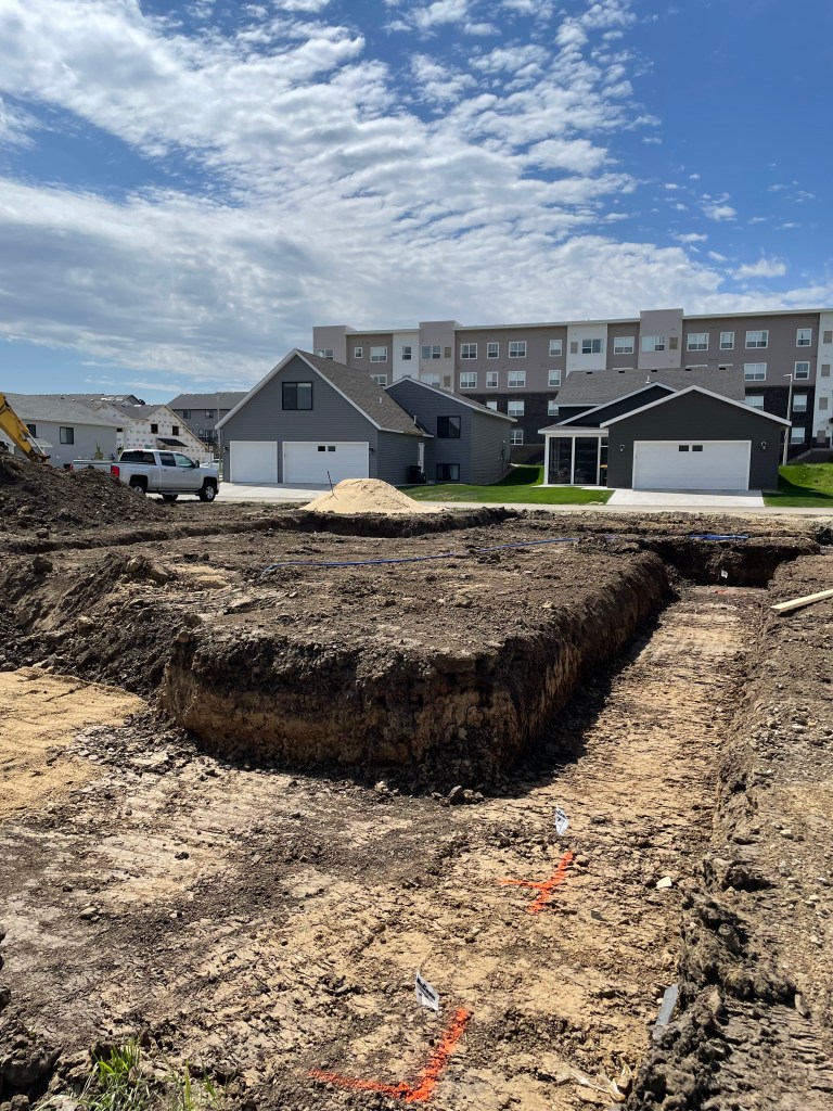large trough in dirt with houses in background