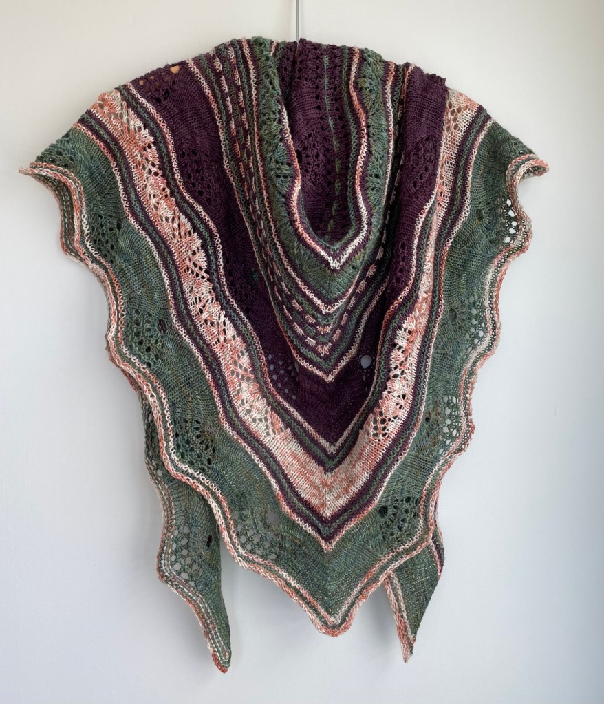 handknit shawl in purple, green, and peach colors on a white background