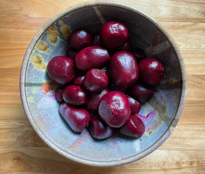 beets in a blue pottery bowl setting on a wood counter