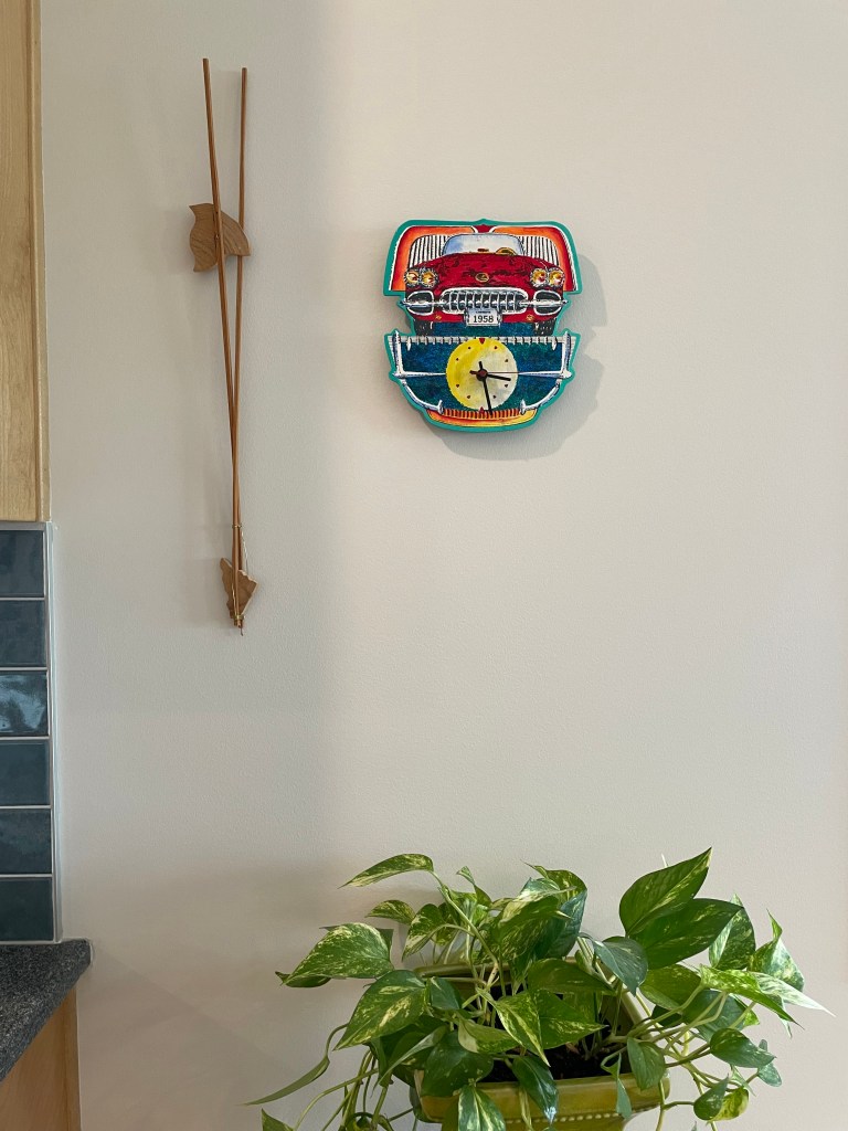 whisical car clock, wooden sculpture, and green plant