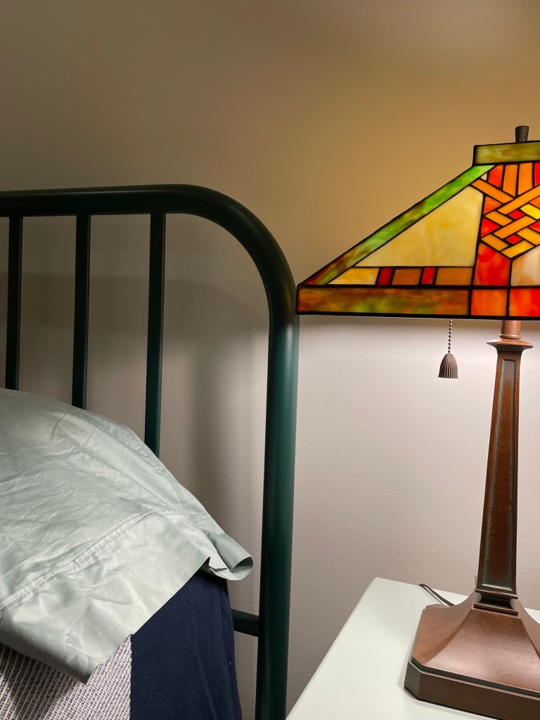 forest green headboard and yellow-orange stained glass lamp shade