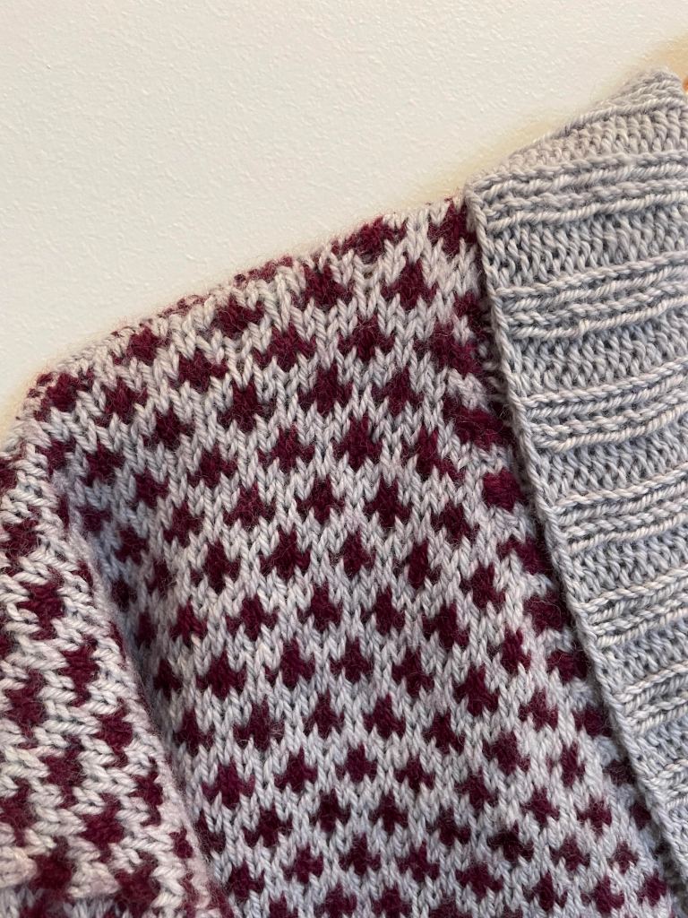 close up of shoulder and collar of a handknit sweater in silvery gray and maroon checks