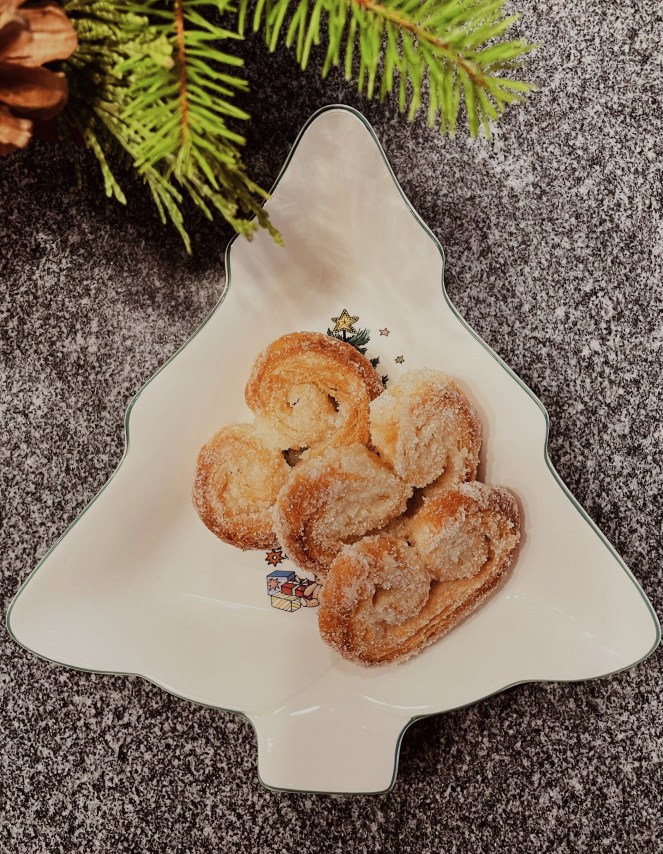 three french palmier cookies on a white christmas tree shaped plate