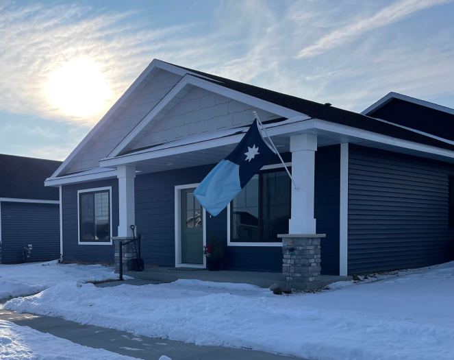 blue house with snow, Minnesota flag and wintery morning sun