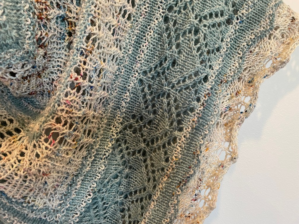 close up of knitting stitches in blue and cream lace shawl