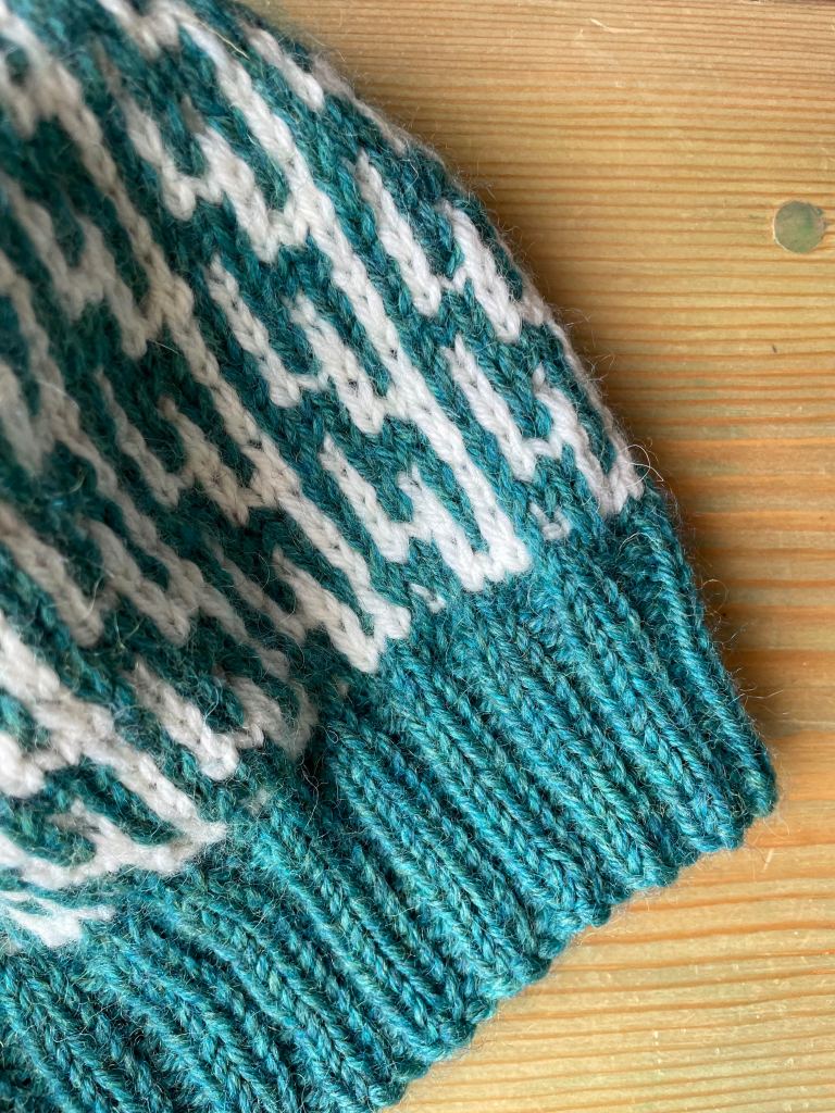 detail of a green and cream colored beanie with a geometric design