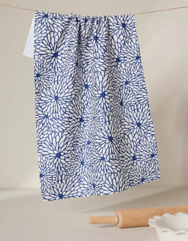 blue and white flowered towel hanging on a wire with a rolling pin and a pie plate in the lower right corner
